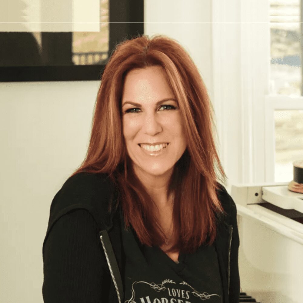 Smiling woman with long red hair sitting indoors.