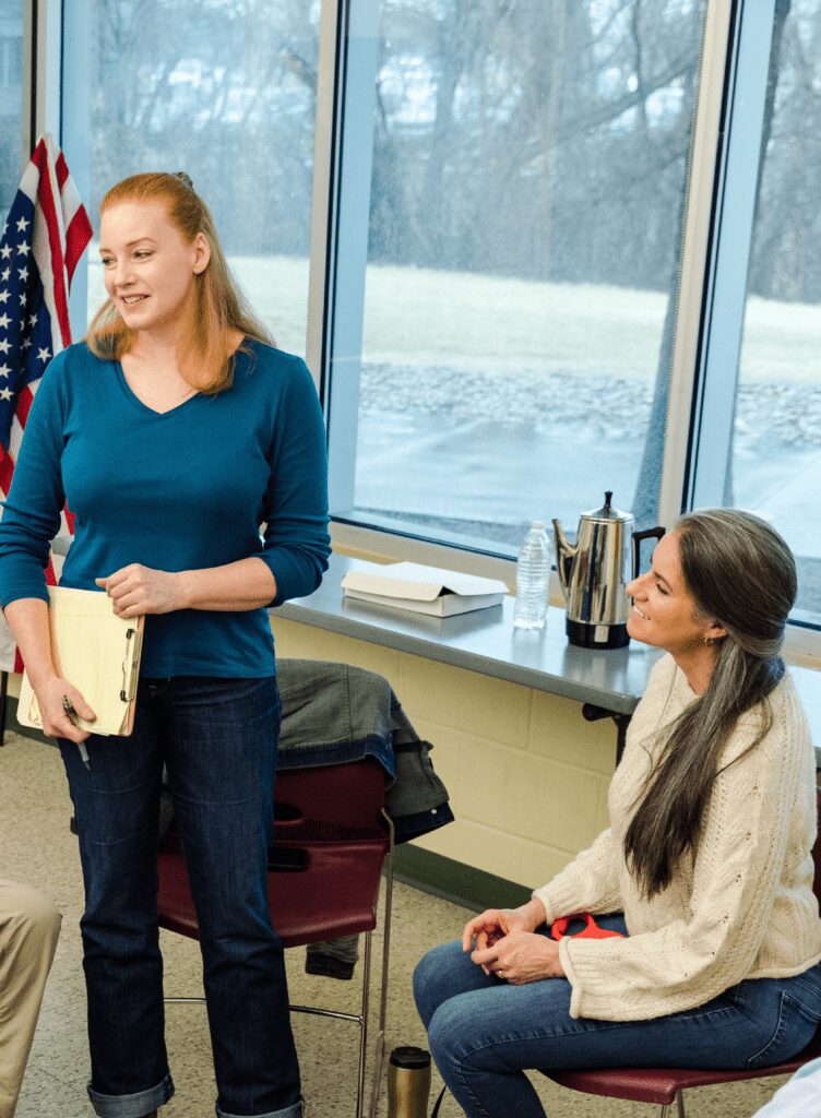 Two women engaged in a casual conversation in a bright room.