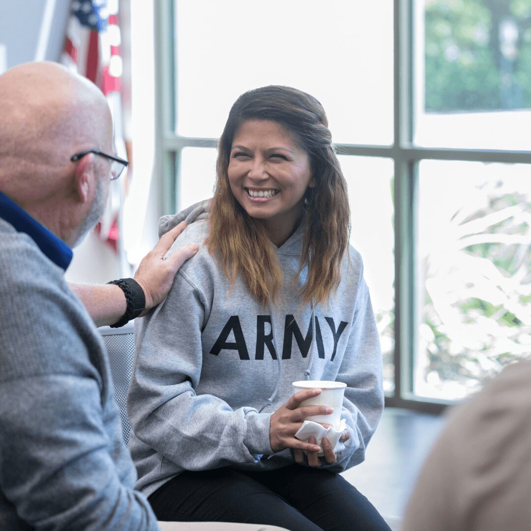 Smiling woman in Army hoodie holding a cup